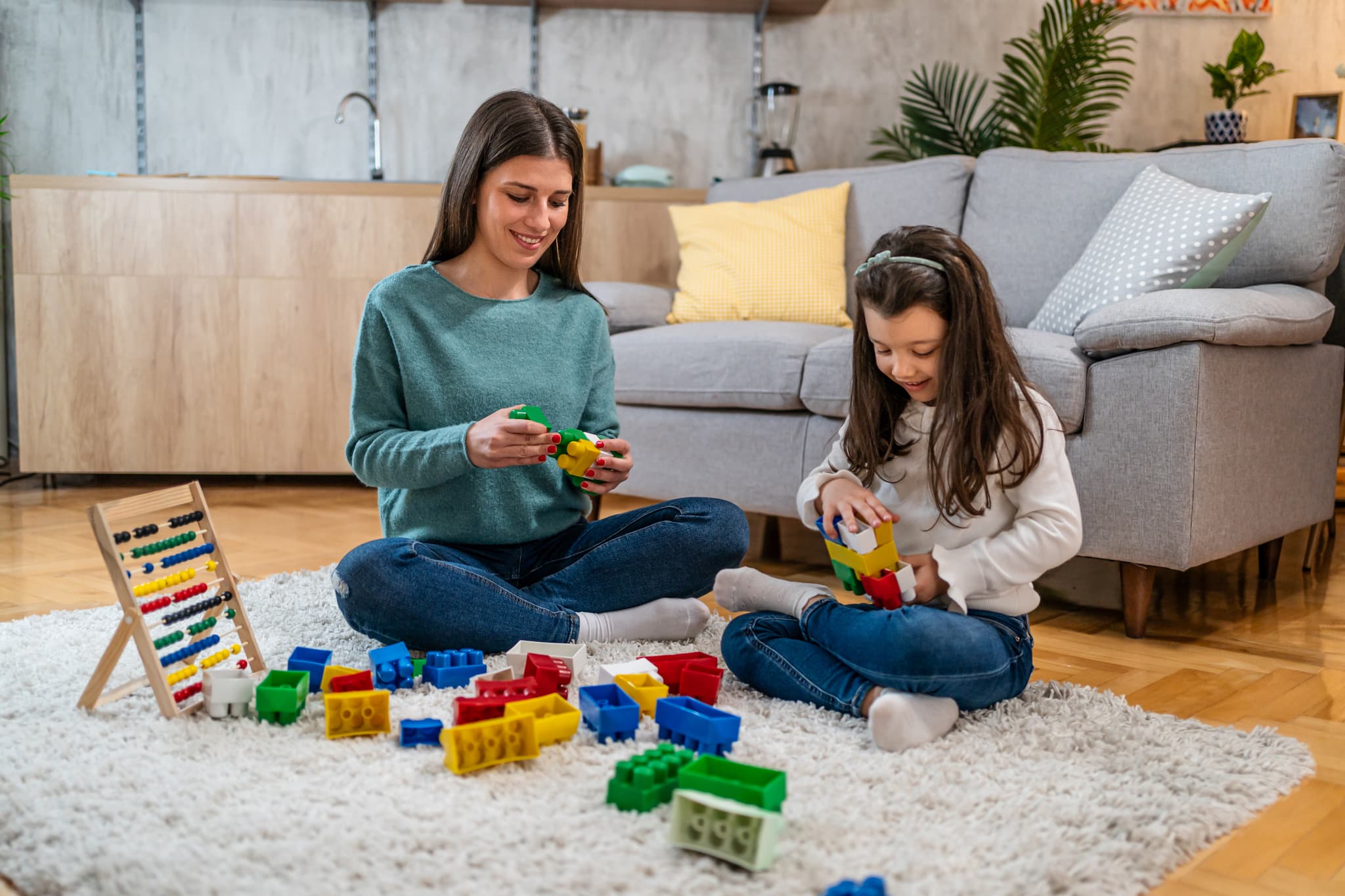 Child and therapist playing with colorful building blocks on the floor